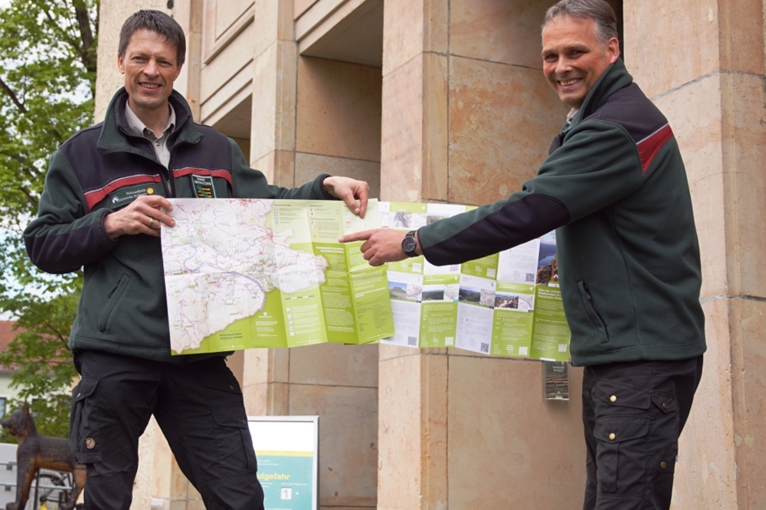 Die Leiter der Nationalparkverwaltung und des Forstbezirks Neustadt Ulf Zimmermann und Uwe Borrmeister stellen den heute erschienen Flyer der Wanderempfehlungen vor dem NationalparkZentrum vor. Dort in Bad Schandau in der Dresdener Straße 2 b können Interessierte sich das Faltblatt abholen. Sobald es möglich ist, liegt das Faltblatt auch in den Touristinformationsstellen aus.