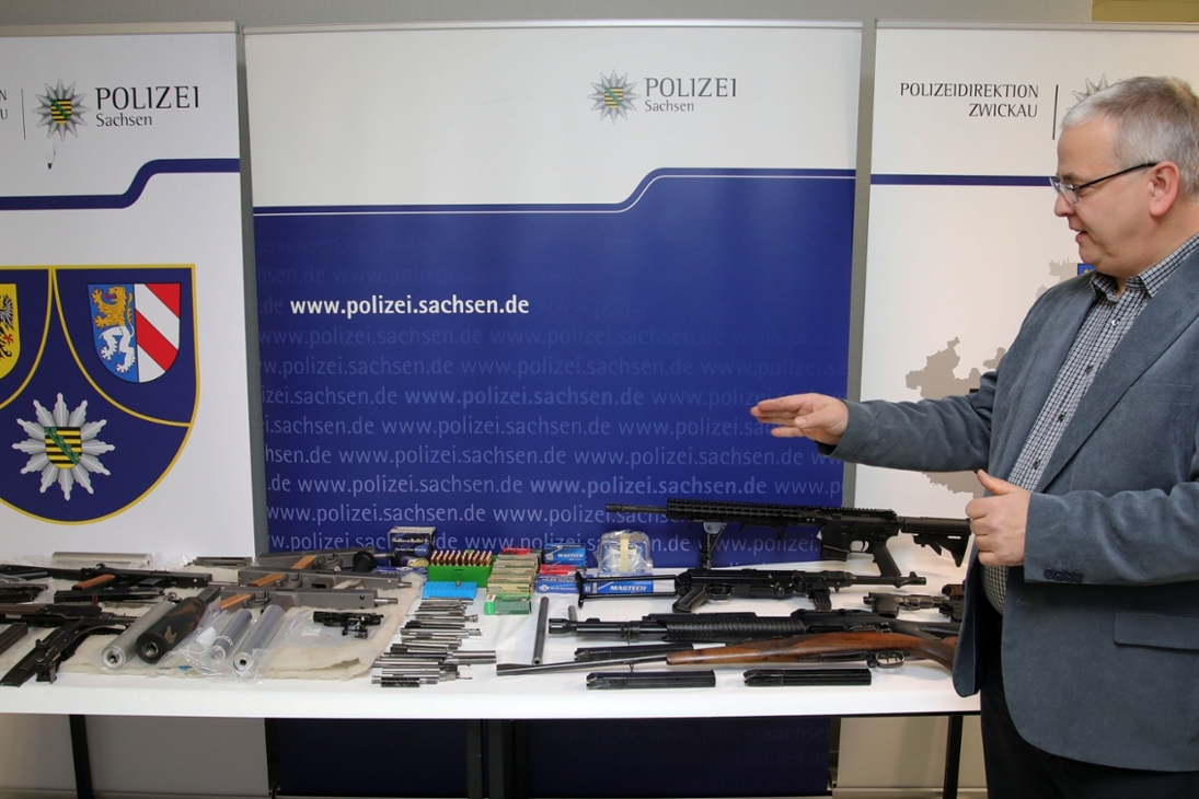 Ein Kriminalbeamter mit einem Teil der gefundenen Waffen und Munition