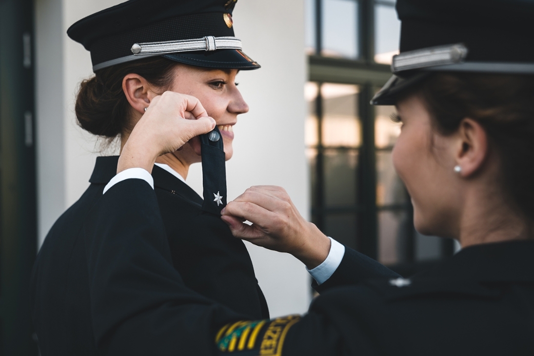 Studierende des 26. Jahrganges der Hochschule der Sächsischen Polizei (FH) stecken sich nach der Ernennung zum Kommissar die neuen Dienstgradabzeichen auf die Uniform.