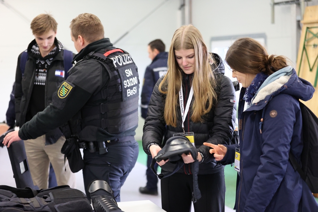 Besucher und Besucherinnen des Hochschulinformationstages an der Hochschule der Sächsischen Polizei (FH) begutachten die polizeiliche Einsatzausrüstung