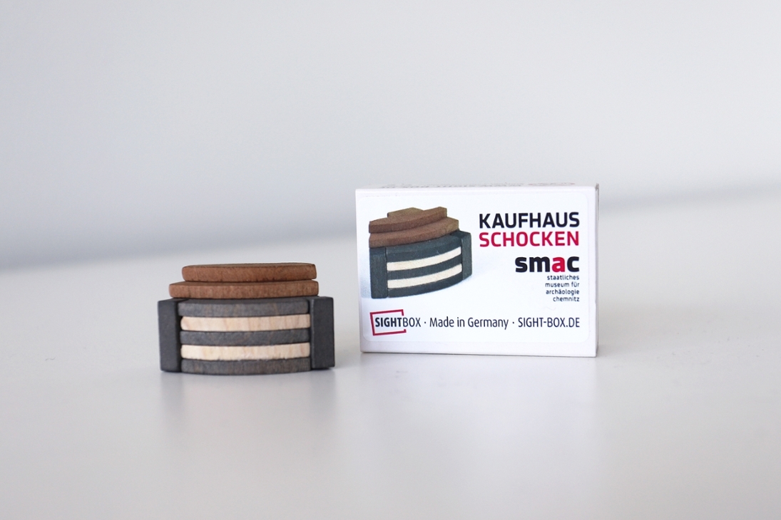 Für 7,95 EUR kann der Schocken-Minibausatz im Museumsshop des smac erworben werden. Die Einzelteile sind in einer Streichholzschachtel verpackt.