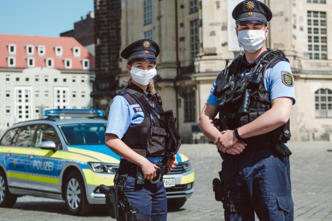 Zwei Einsatzbeamte der sächsischen Polizei vor der Frauenkirche in Dresden tragen die Community-Maske