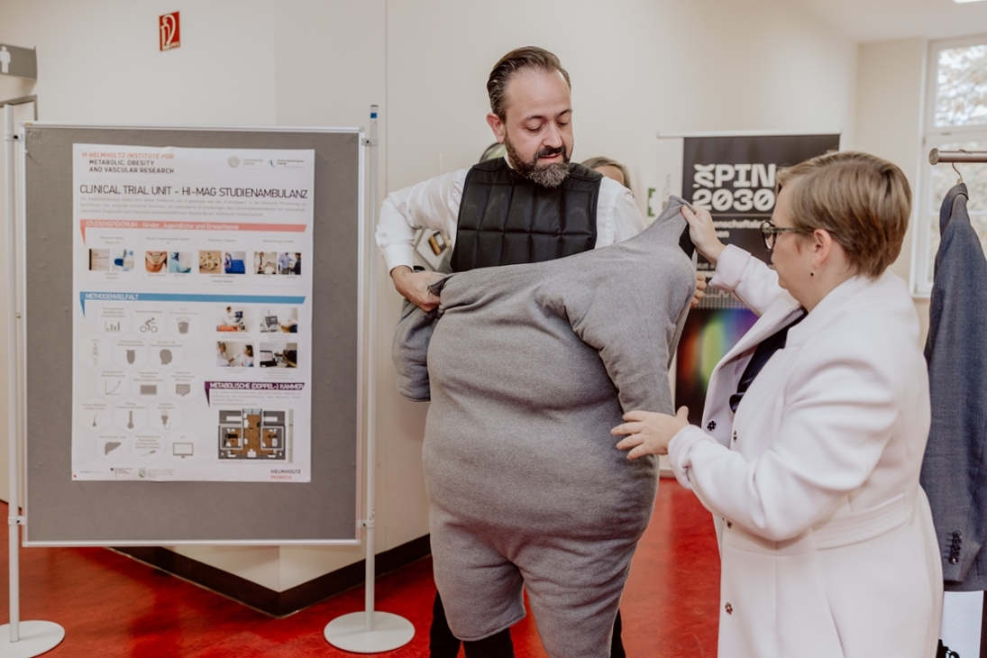 Besuch von Wissenschaftsminister Gemkow am Helmholtz-Institut für Metabolismus, Adipositas und Gefäßforschung (HI-MAG) in Leipzig. Der Adipositasanzug soll helfen, für das Thema zu sensibilisieren.