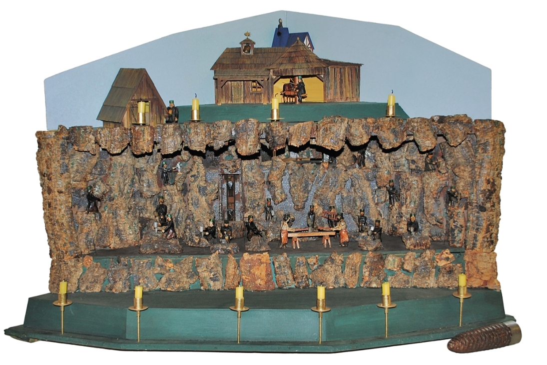 Mechanisiertes und elektrifiziertes Stufenbergwerk,
wohl Annaberg, 2. Hälfte 19. Jh.
Maße: 78 x 115 x 70 cm
Der Antrieb des Bergwerkes erfolgt mechanisch durch ein Gewicht aus Gusseisen und Blei. Auch ein Berggeist ist Teil der Szenerie, welcher durch das automatische Öffnen einer Klappe – mit vorheriger Ankündigung durch einen Glockenschlag – kurz erscheint.
Schenkung von Privat um 1960.