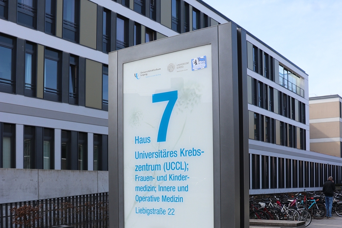 Außenaufnahme des Gebäudes des Universitären Krebszentrums in Leipzig mit Wegweiser UCCL im Vordergrund