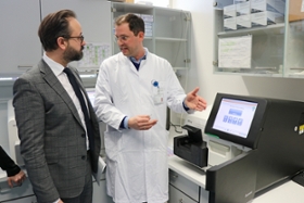 Foto: Wissenschaftsminister Gemkow im Gespräch Universitätsproffessor von Laffert vor einem Gerät ds Tumorproben sequenziert und die molekulare Zusammensetzung von Turmorgewebe bestimmt.