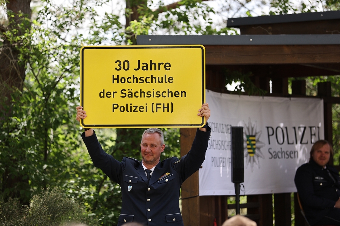 Erster Polizeihauptkommissar Thomas Knaup präsentiert den Anlass des Festaktes auf e nem nachempfundenen Verkehrsschild.