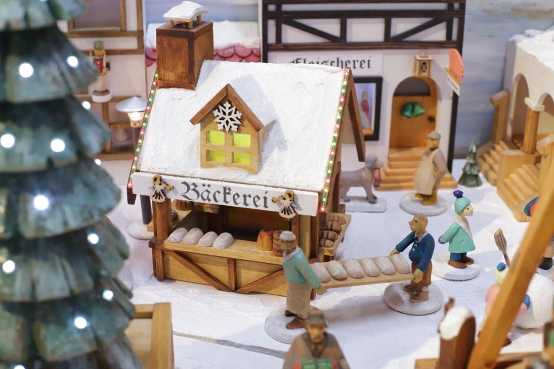 Detail aus dem Heimatberg von Holger Rockstroh mit Weihnachtsmarktstand einer Bäckerei und fachwerklicher Bebauung des Marktplatzes.