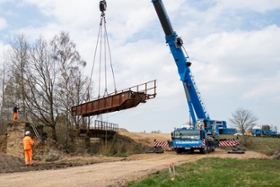 Foto: Ein Teil der alten Eisenbahnbrücke, die über den Holzbach führte, wird durch einen Kran ausgehoben.
