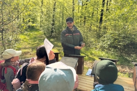 Foto: Forstinspektoranwärter Jonas Andruschek mit Schülerinnen und Schülern an einer Station mit Tastboxen