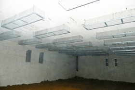 Foto: Fledermaussteine an einer Bunkerdecke, Boden mit Sandschüttung zur Feuchteregulation, im Hintergrund Wasserzufluss von der Bunkerdecke