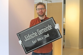 Foto: Kurator Dr. Alexander Walther mit der DDR-zeitlichen Emaille-Plakette der Jüdischen Gemeinde Chemnitz, damals Karl-Marx-Stadt.