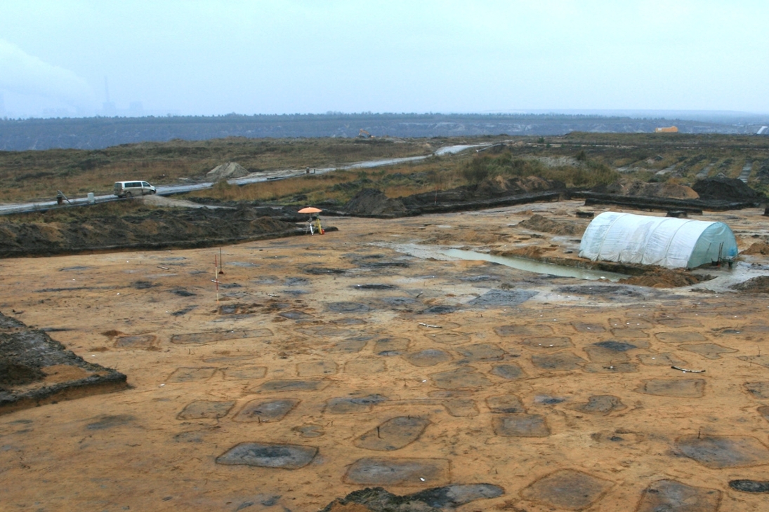 Die Pechgruben bedecken neben dem Ofen eine weite Fläche. Im Hintergrund ist am Horizont das Kraftwerk Boxberg erkennbar.